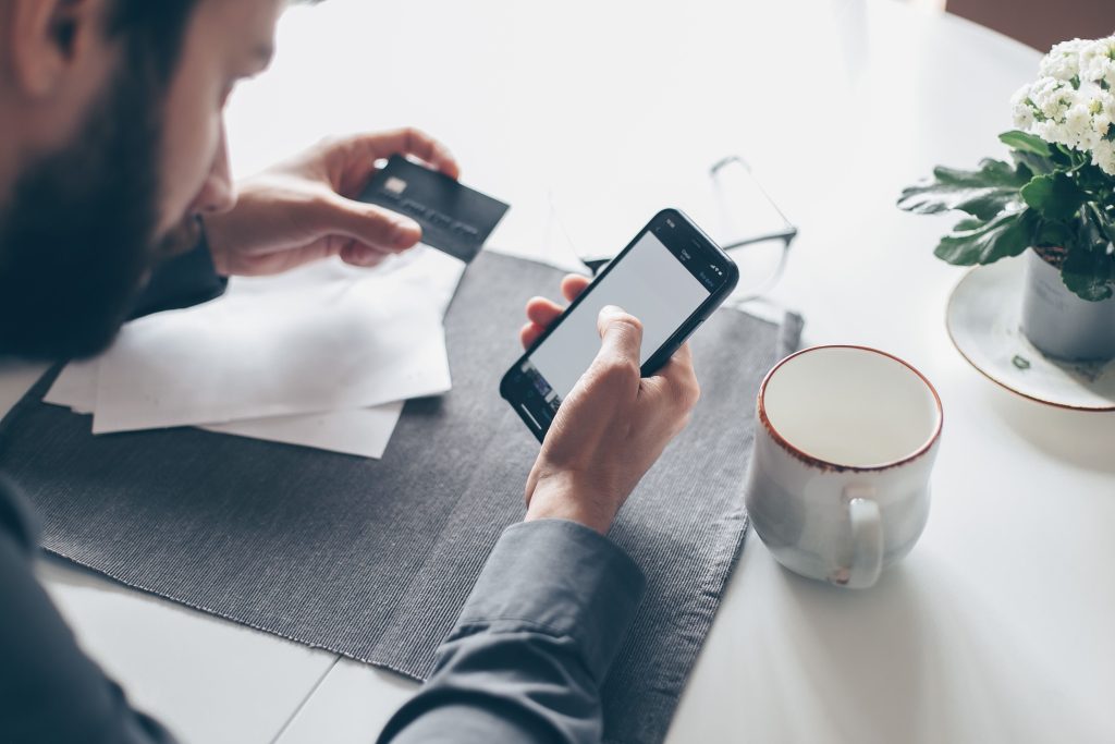 Person holding credit card and smartphone while using a mobile banking app