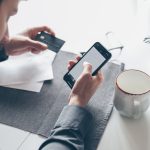 Person holding credit card and smartphone while using a mobile banking app