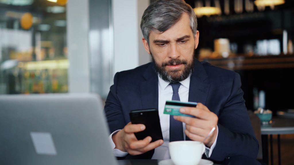 Man checking bank account security on smartphone while holding a credit card