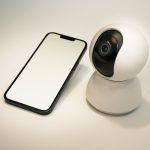 phone lying next to a small spy camera representing phone surveillance